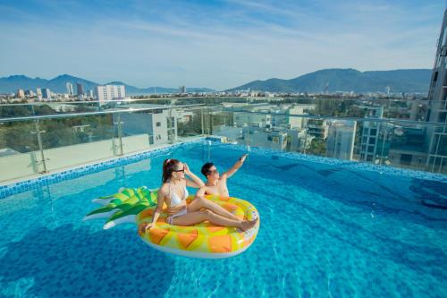 two women are sitting on an inner tube in a swimming pool at Pharaoh Boutique Hotel Danang in Danang