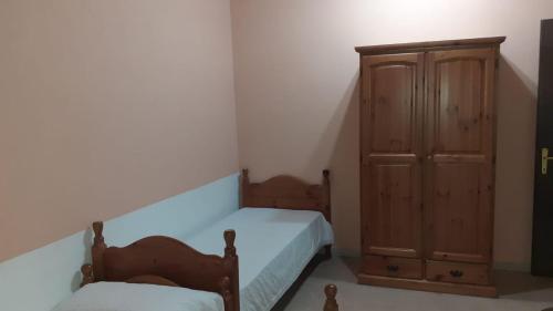 1 dormitorio con 1 cama y armario de madera en Agriturismo S'Armidda, en Seùlo