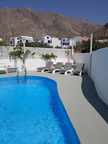 a swimming pool with chairs and a view of the mountains at Three Harites in Perissa