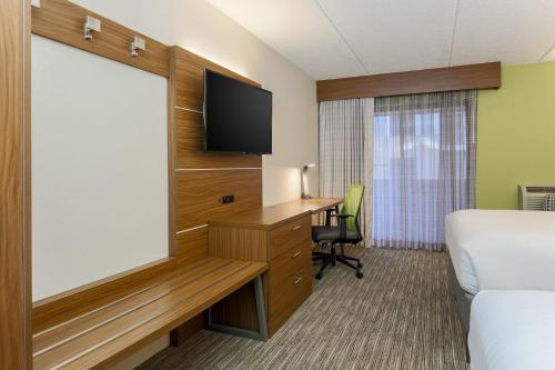 a hotel room with a flat screen tv and a desk at Holiday Inn Express Milwaukee - West Medical Center by IHG in Wauwatosa