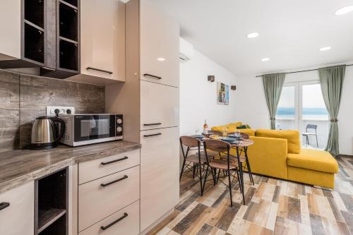 eine Küche und ein Wohnzimmer mit einem gelben Sofa und einem Tisch in der Unterkunft Villa Zita Lovran in Opric