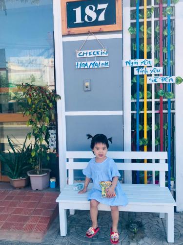 a little girl sitting on a bench in front of a store at Hoa Mai Hotel in Dong Hoi
