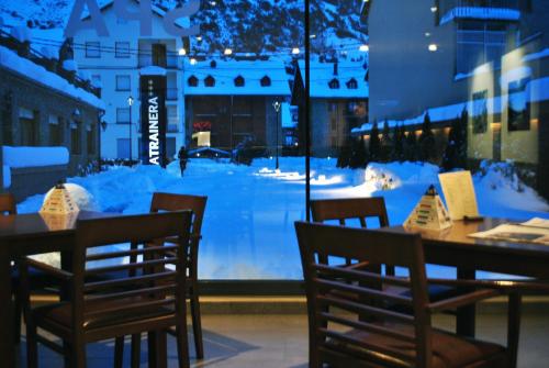 a restaurant with tables and chairs and a snow covered street at Aparthotel Trainera in Esterri d'Àneu