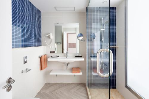 a bathroom with a glass shower and a sink at Hotel Riu Papayas - All Inclusive in Playa del Ingles