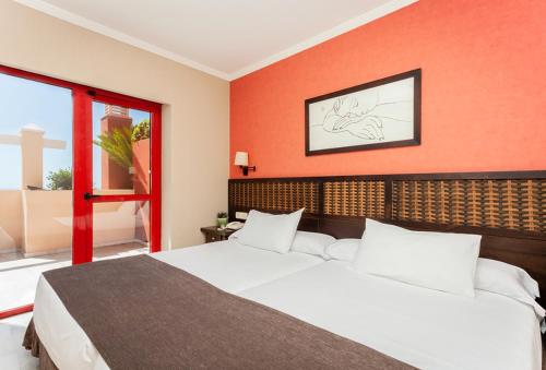 1 dormitorio con cama blanca y pared roja en Holiday Premium Resort, en Benalmádena