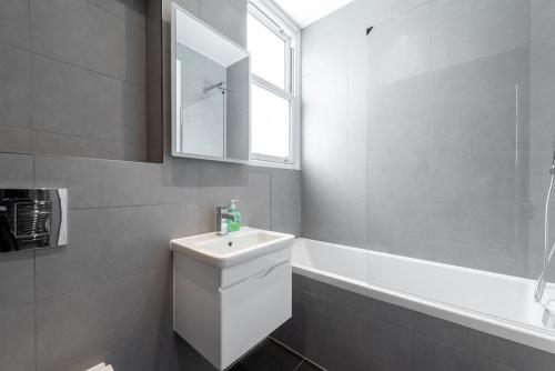 a white bathroom with a sink and a bath tub at Hyde Park Apartment (SS1) in London