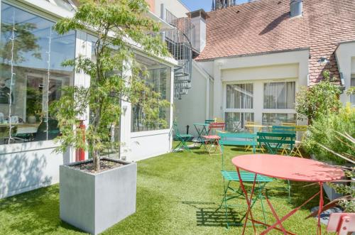 a patio with a table and chairs and a tree at La Maison Hôtel Mulhouse Centre in Mulhouse