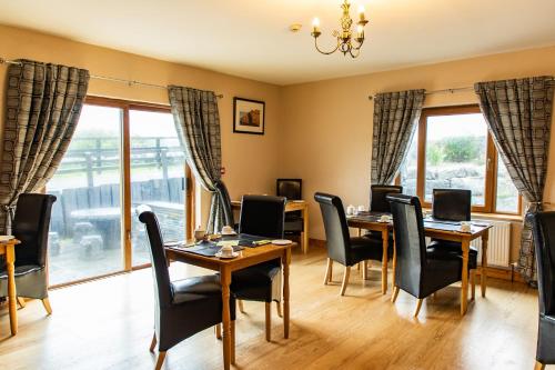 a dining room with tables and chairs and windows at Twin Peaks B&B in Doolin