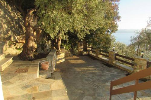 a pathway with trees and a fence and the ocean at Το Σπιτι με την Σπηλιά in Platanias