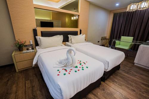 a hotel room with two beds with a swan on it at JC Mark Hotel in Bintulu