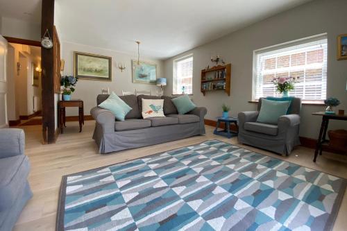 a living room with a couch and two chairs and a rug at Delf Stream, close to town with lovely sunny terrace in Sandwich