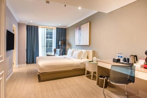 a hotel room with a bed and a desk at Ashley Sabang Jakarta in Jakarta