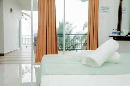 a bedroom with a white bed and a balcony at Araliya Lagoon Park Resort in Negombo