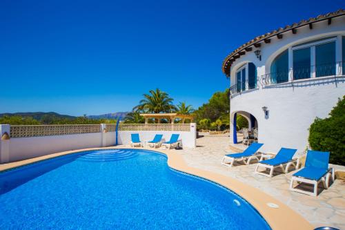 a swimming pool with chairs and a house at Mirador al Sur in Moraira