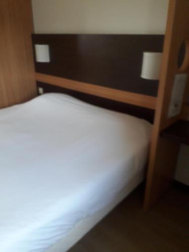 a bedroom with a bed with a wooden head board at Première Classe Annemasse Ville La Grand in Ville-la-Grand