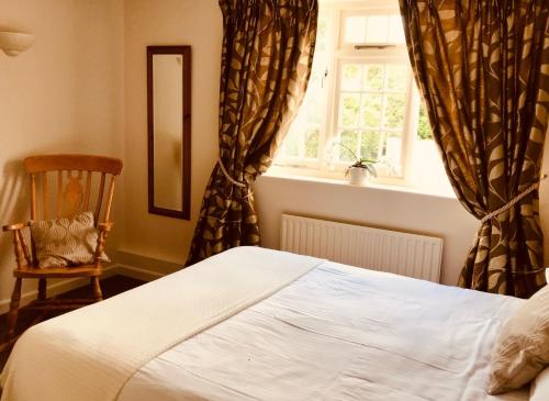 a bedroom with a bed and a chair and a window at The Barford Inn in Salisbury