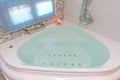 a blue bath tub in a bathroom with a window at Yejeon Pension in Gyeongju