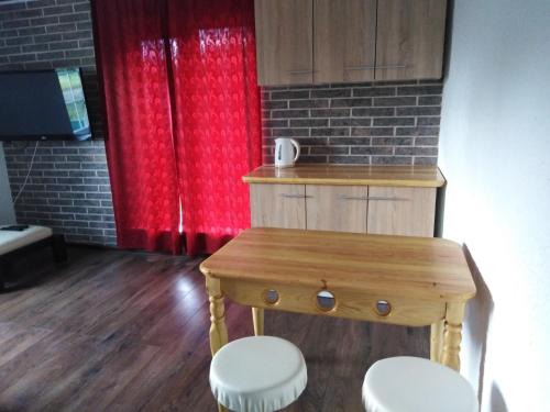 une cuisine avec une table en bois et un rideau rouge dans l'établissement Гостевая комната, à Kiev
