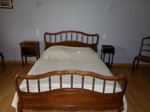 a wooden bed in a room with two chairs at Gîte Clévacances dans le Finistère in Scrignac