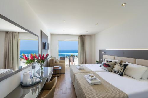 a bedroom with a large bed and a living room at Queens Bay Hotel in Paphos