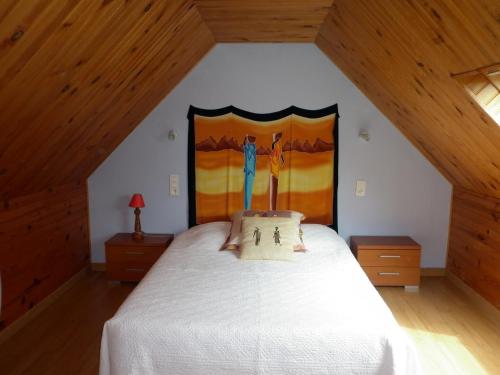 een slaapkamer met een wit bed en een schilderij aan de muur bij Gîte Clévacances dans le Finistère in Scrignac