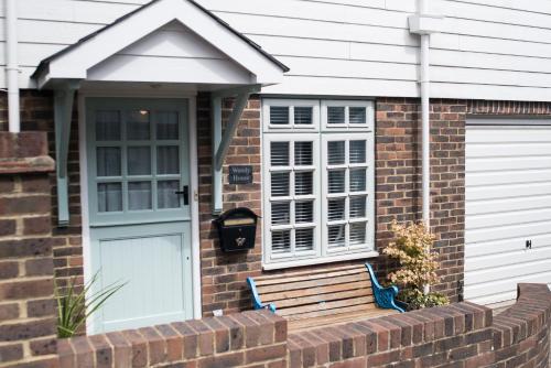 a brick house with a blue door and a bench at Wendy House in Eastbourne