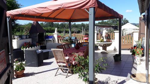 een patio met een parasol en een tafel en stoelen bij l orchidee in Hérisson