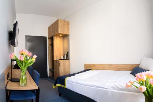 a bedroom with a bed and a table with flowers at Hotel Mokotów in Warsaw