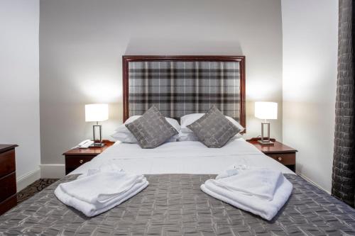 a bedroom with a large bed with two towels on it at Carrbridge Hotel in Carrbridge
