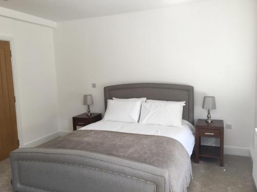 a bedroom with a large bed with two night stands at Beautiful 1 BED Serviced APARTMENT COBHAM Town Centre in Cobham