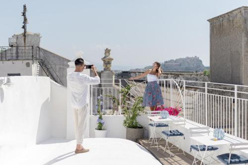 Un uomo che scatta una foto a una donna su un balcone di Le Volte Procida Home a Procida