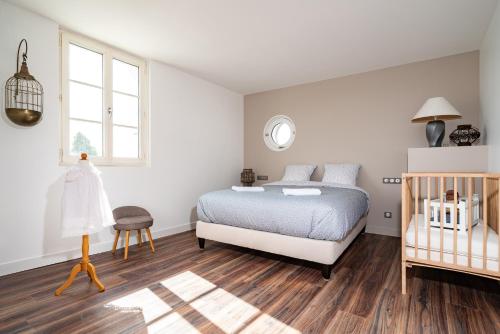 a white bedroom with a bed and a crib at L'Auberge du Croissant in Rochecorbon