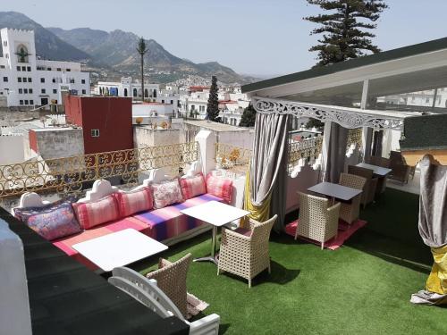 einen Balkon mit einem Sofa, Tischen und Stühlen in der Unterkunft El Reducto in Tétouan