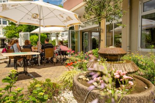 a garden with people sitting at tables and umbrellas at Hotel Krupp in Bad Neuenahr-Ahrweiler