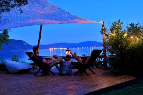 two people sitting at a table under an umbrella at Beach front Villa Melani in Mytilini