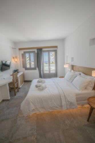 a bedroom with a large white bed and a bathroom at Eternity Suites Santorini in Fira