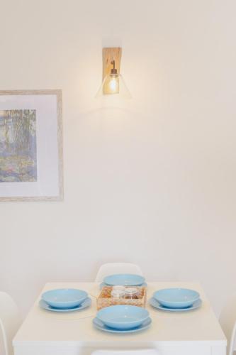 a table with four blue plates and a light at Le Volte Procida Home in Procida