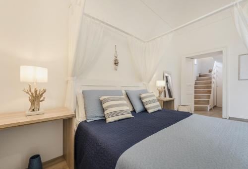 a white bedroom with a blue bed with pillows at Le Volte Procida Home in Procida