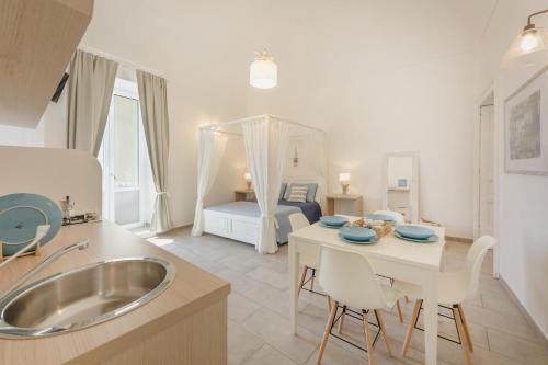 a kitchen with a sink and a table and a bed at Le Volte Procida Home in Procida