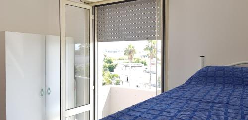 ein Schlafzimmer mit einem blauen Bett und einem Fenster in der Unterkunft Appartamenti Rivabella Gallipoli in Rivabella