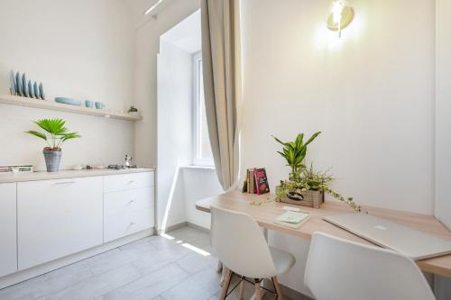 a kitchen with white cabinets and a table and chairs at Le Volte Procida Home in Procida