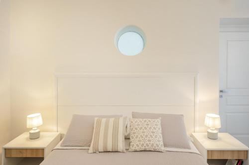 a white bedroom with a bed with two lamps at Le Volte Procida Home in Procida