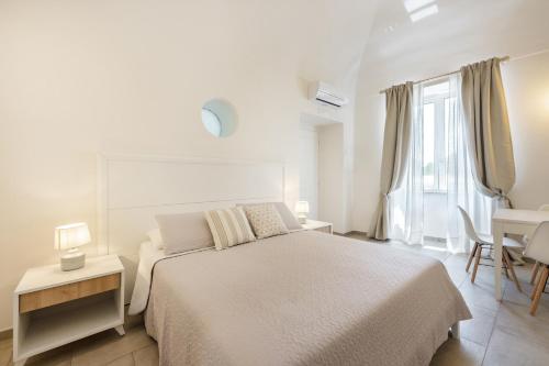 a white bedroom with a large bed and a desk at Le Volte Procida Home in Procida