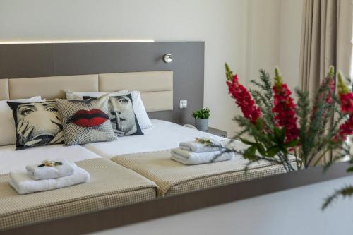 
a bed with two pillows and a vase of flowers at Queens Bay Hotel in Paphos

