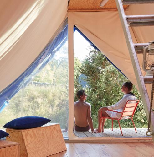 two men sitting on a porch in a tent at La Belle Folie in Ploemel