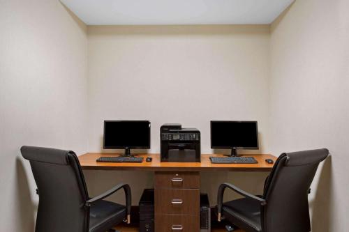 two computer monitors sitting on a desk with chairs at La Quinta by Wyndham Springfield in Springfield