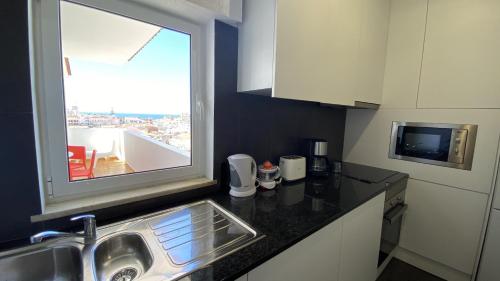 een kleine keuken met een wastafel en een raam bij Rooftop by Check-in Portugal in Albufeira