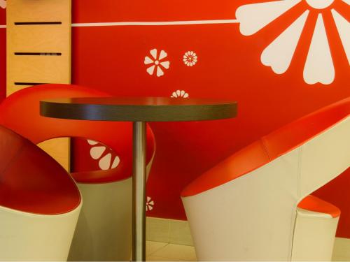 a red wall with red chairs and a table at ibis Porto Centro São Bento in Porto