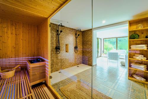 uma casa de banho com um chuveiro e uma porta de vidro em Yael Luxury Apartments 3 em Buşteni
