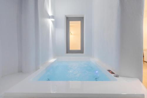 a white bath tub in a white room with a window at Eternity Suites Santorini in Fira